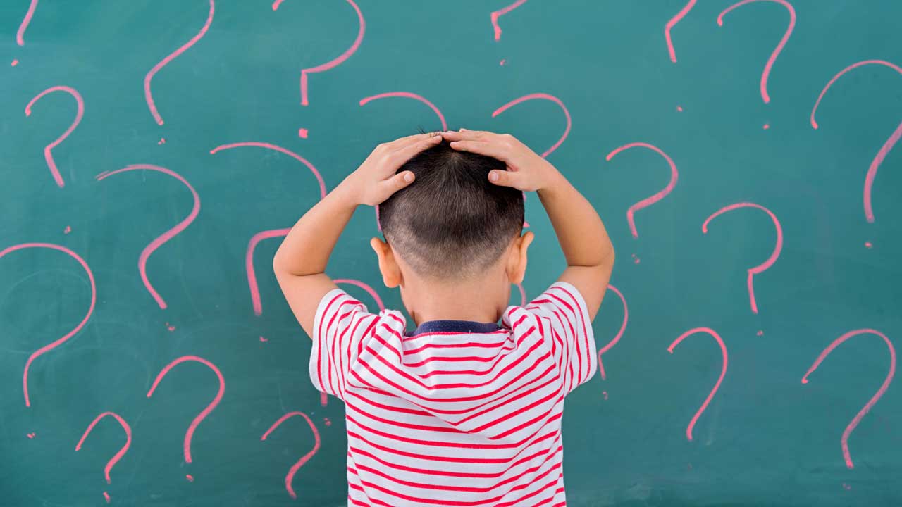 [a kid looking confused at a blackboard filled with question marks]
